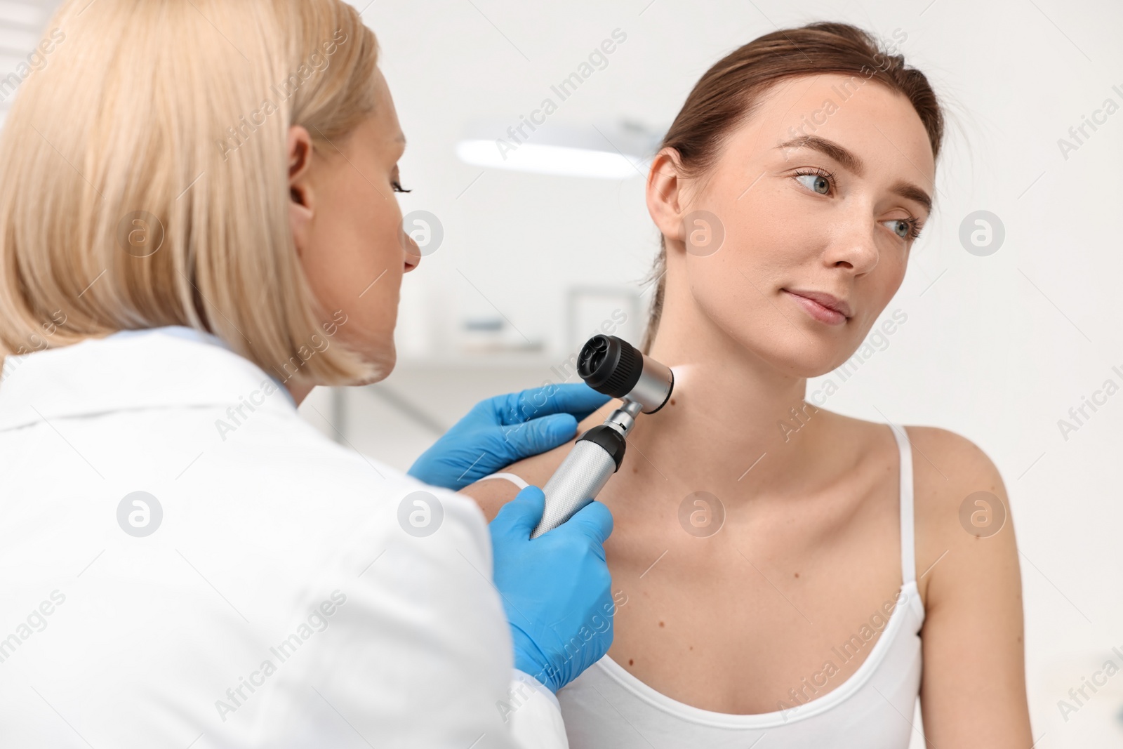 Photo of Dermatologist with dermatoscope examining patient in clinic