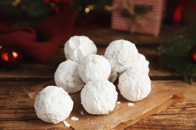 Photo of Tasty snowball cookies and Christmas decorations on wooden table, closeup