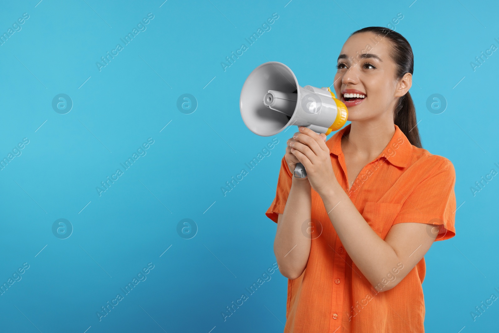 Photo of Special promotion. Smiling woman with megaphone on light blue background. Space for text