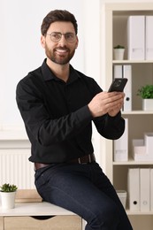 Photo of Smiling man in shirt with smartphone in office