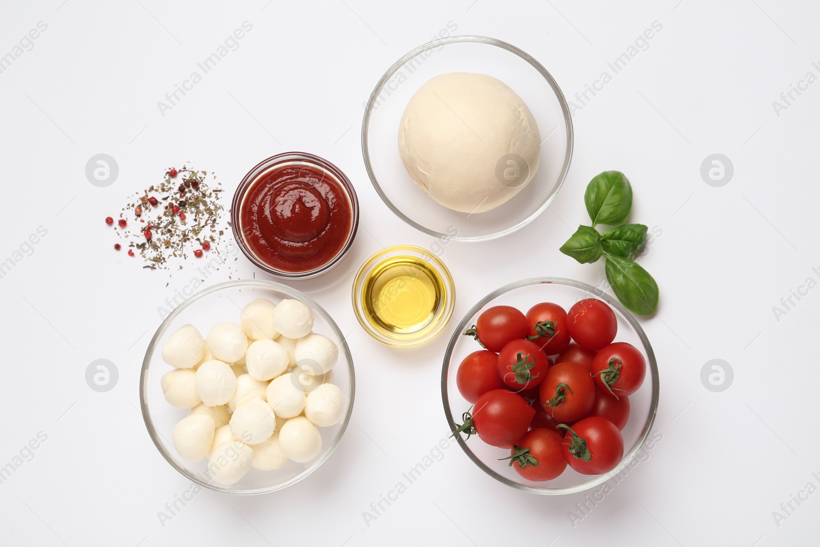 Photo of Raw dough and other ingredients for pizza on white background, top view