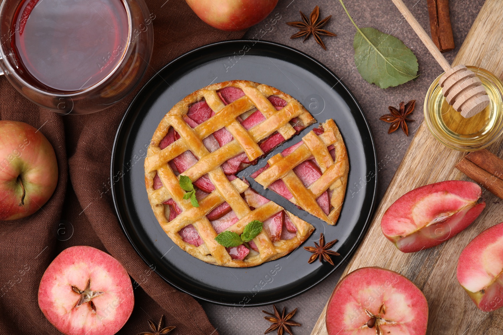 Photo of Delicious apple pie with mint and ingredients on brown table, flat lay