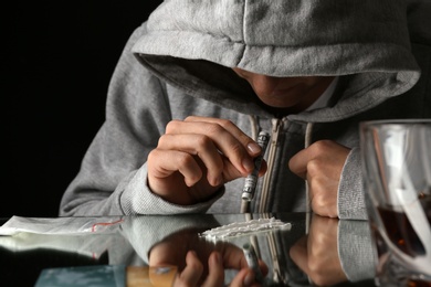Photo of Drug addict taking cocaine at table, closeup view