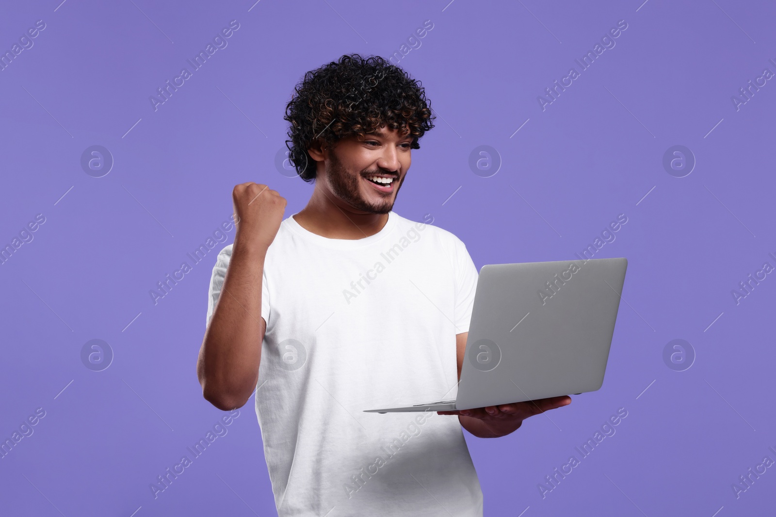 Photo of Happy man with laptop on purple background, space for text