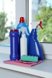 Photo of Different cleaning supplies and tools on window sill indoors