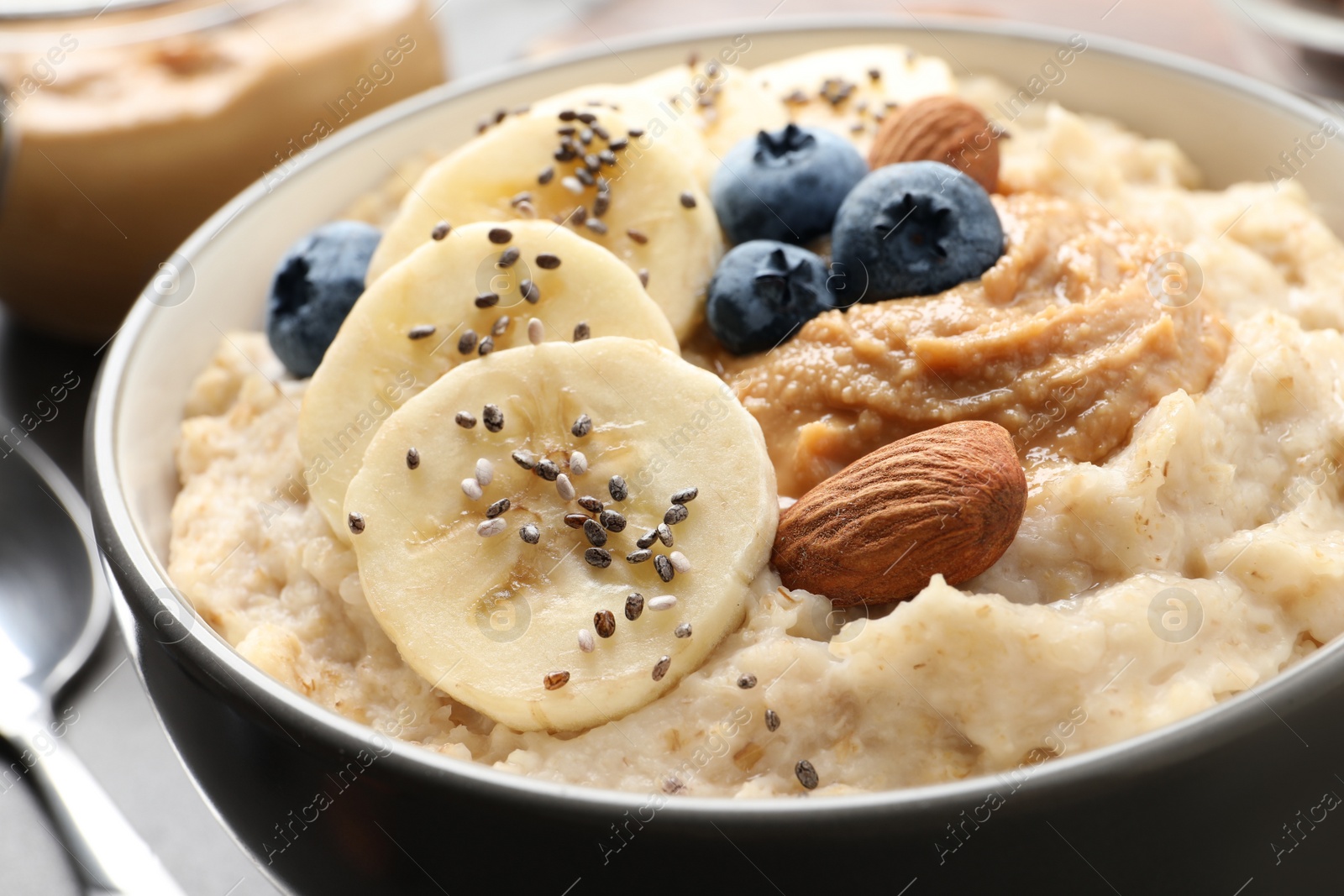 Photo of Tasty oatmeal porridge with toppings in bowl on table, closeup