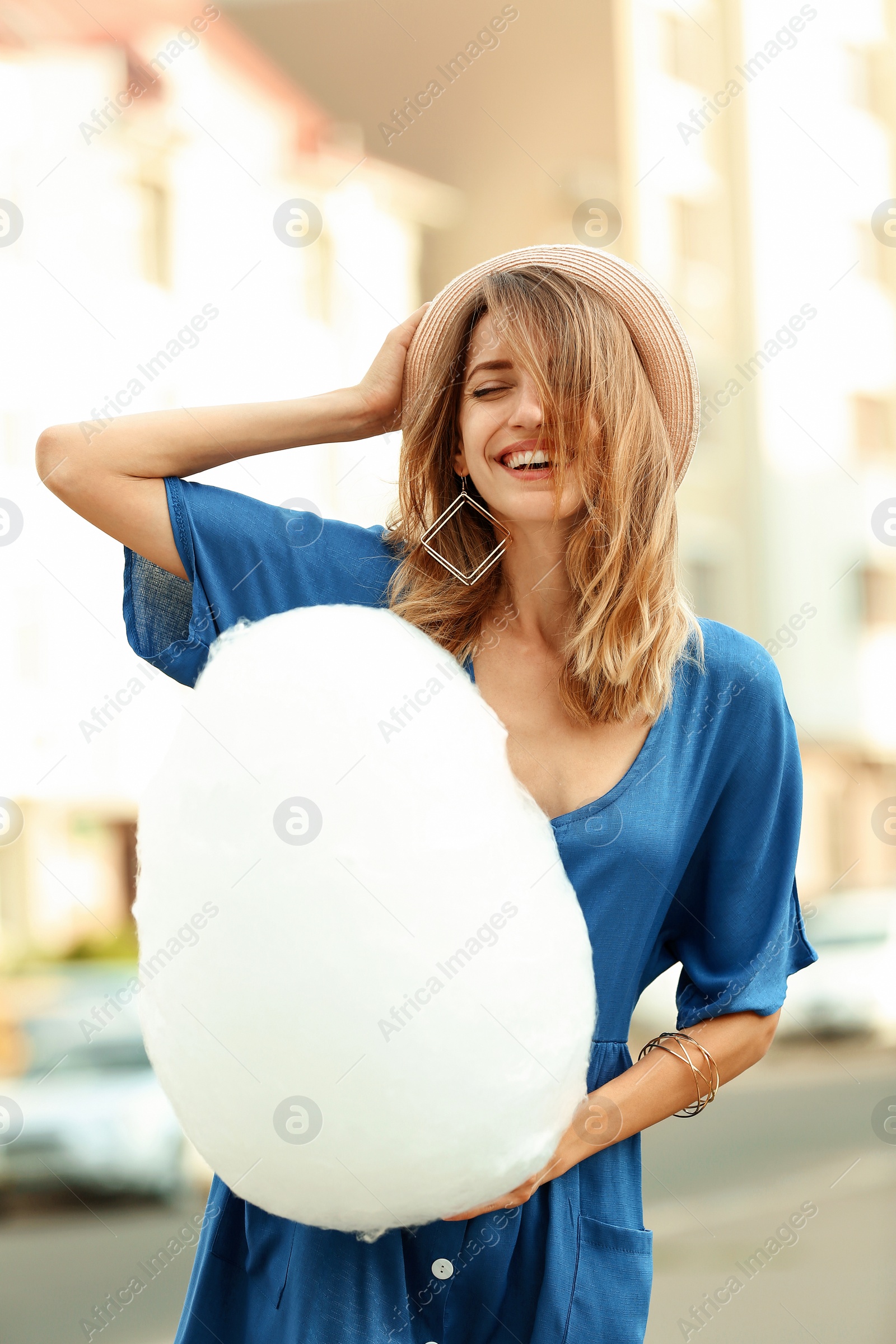 Photo of Happy young woman with cotton candy outdoors