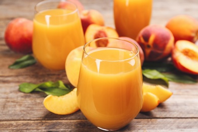 Natural peach juice and fresh fruits on wooden table, closeup