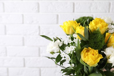 Photo of Beautiful bouquet with peony tulips near white brick wall, closeup. Space for text