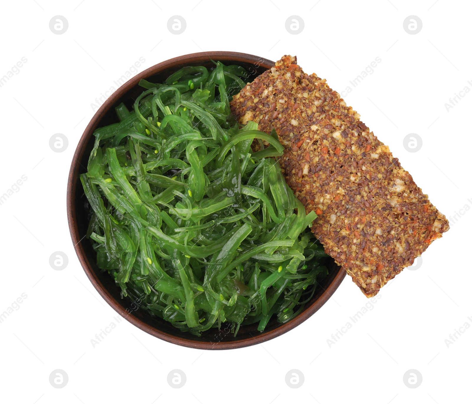 Photo of Tasty seaweed salad in bowl and crispbread isolated on white, top view