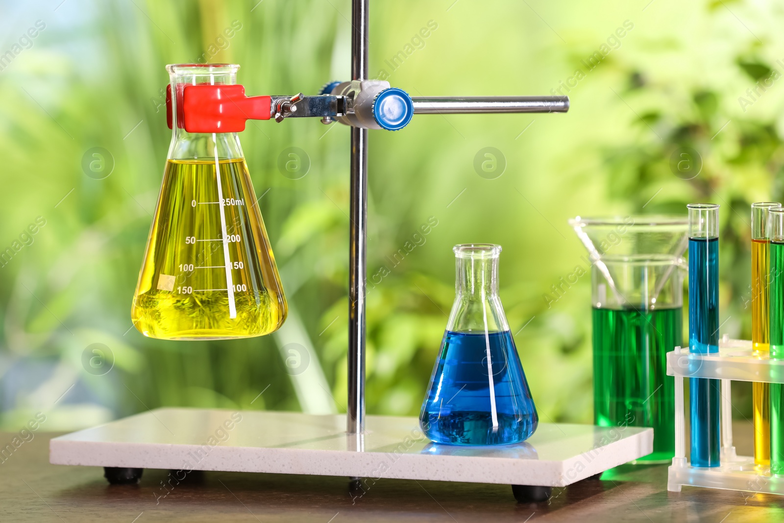 Photo of Laboratory glassware with colorful liquids on table against blurred background