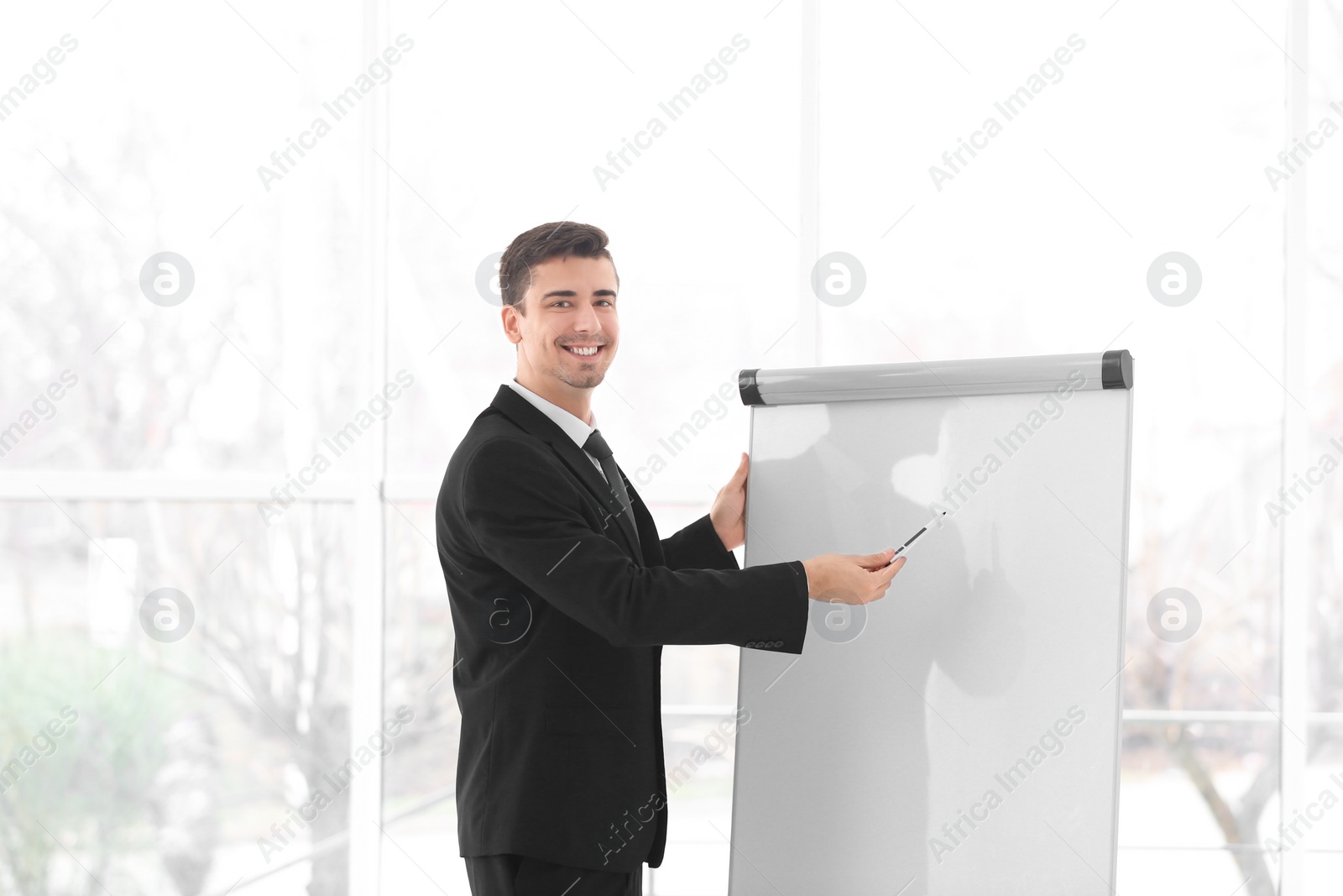 Photo of Business trainer giving presentation on flip chart board indoors