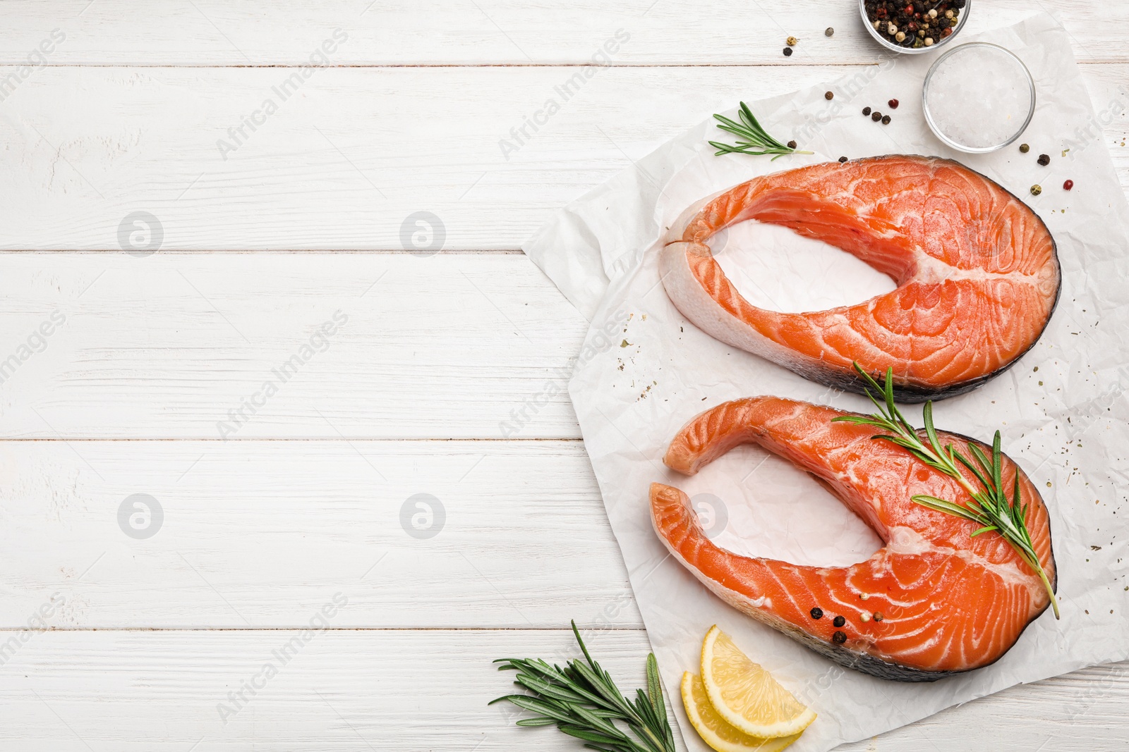 Photo of Flat lay composition with fresh salmon steaks on white wooden table, space for text