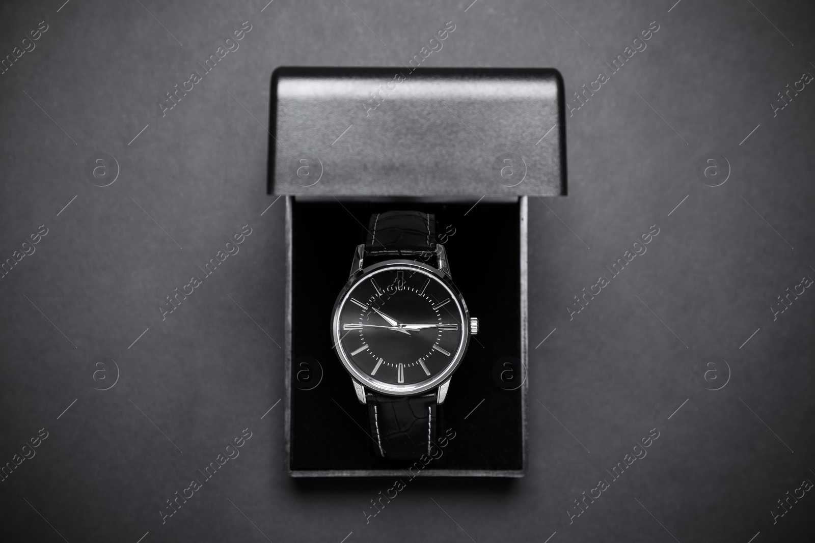 Photo of Elegant wristwatch in box on black background, top view