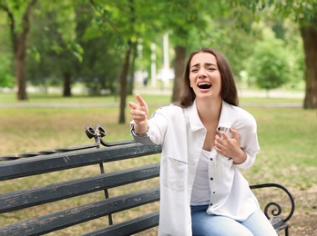 Young woman asking for help while having heart attack in park