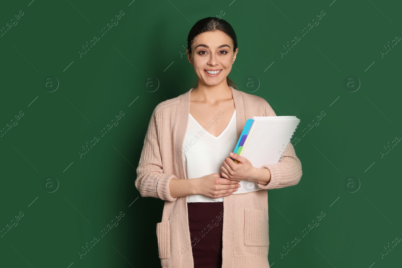 Photo of Portrait of young teacher with notebook on green background
