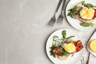 Photo of Delicious eggs Benedict served on light grey marble table, flat lay. Space for text