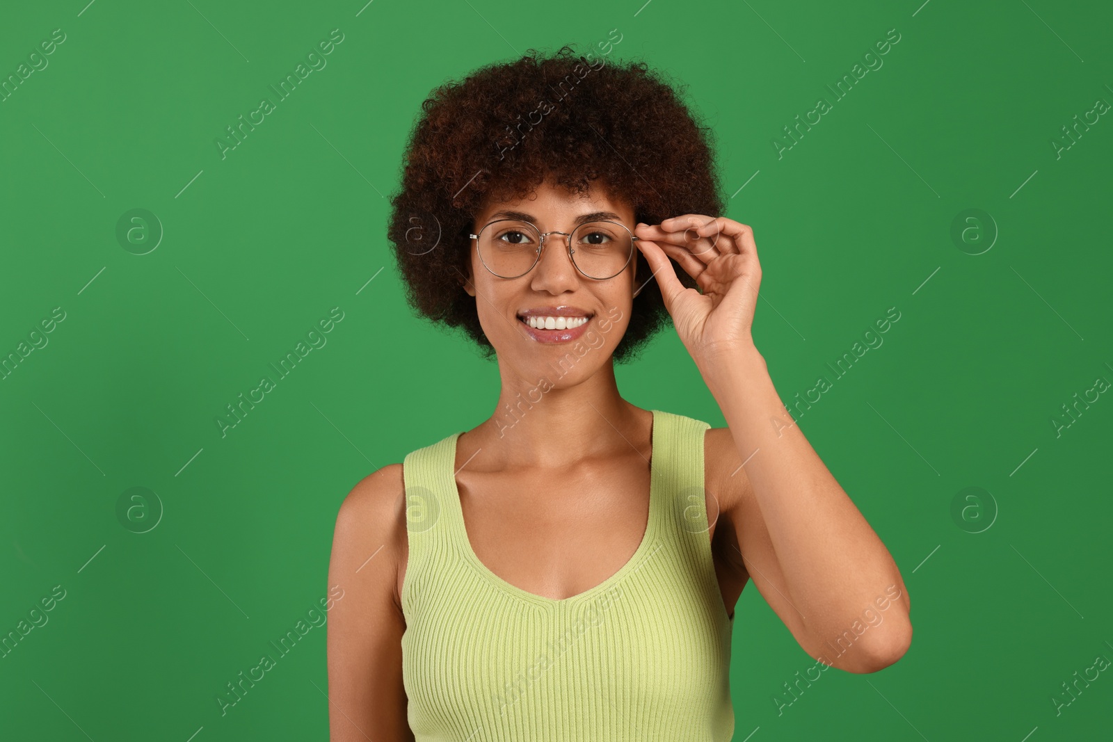 Photo of Portrait of happy young woman in eyeglasses on green background