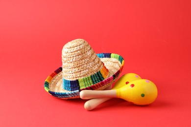 Mexican sombrero hat and maracas on red background