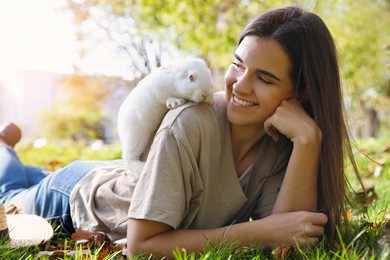 Photo of Happy woman with cute white rabbit on grass in park