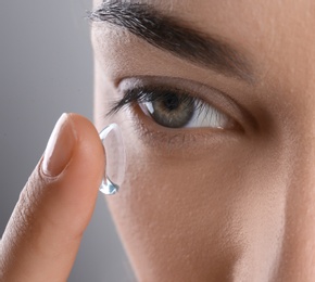 Photo of Young woman putting contact lens in her eye, closeup