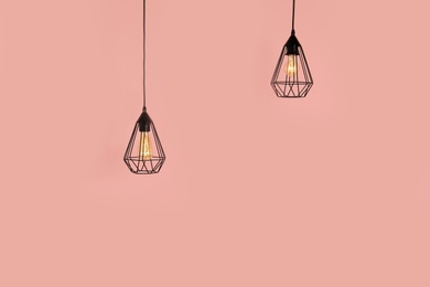 Modern hanging lamps on color background, space for text. Idea for interior design