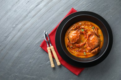 Photo of Delicious boiled crabs with sauce served on grey textured table, top view. Space for text