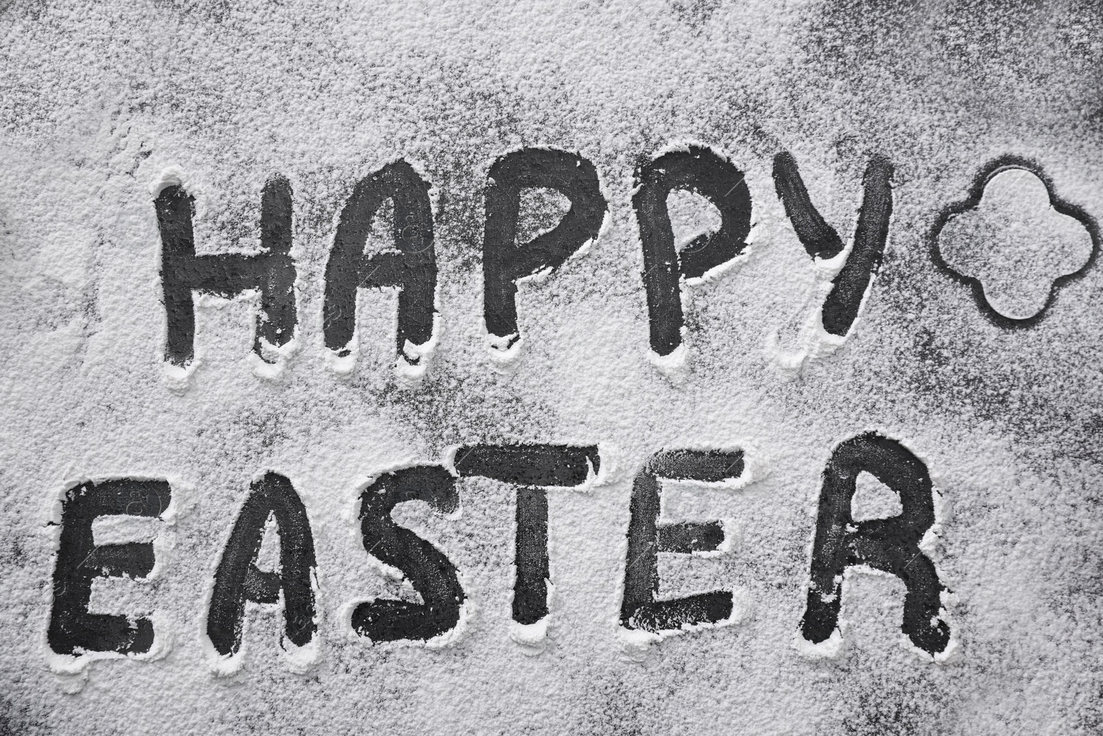 Photo of Words Happy Easter written in flour on black table, top view. Baking cake
