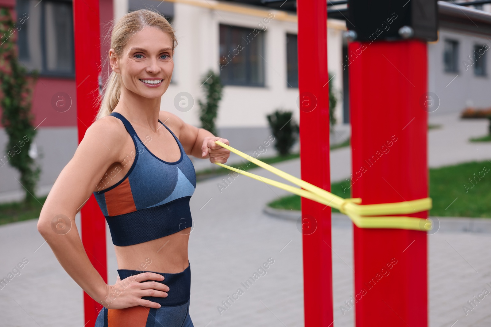 Photo of Athletic woman doing exercise with fitness elastic band at outdoor gym