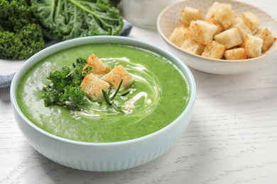 Photo of Tasty kale soup on white wooden table, closeup
