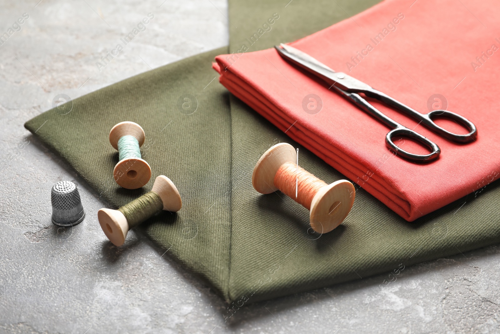 Photo of Scissors, threads and fabric on grey background. Tailoring equipment