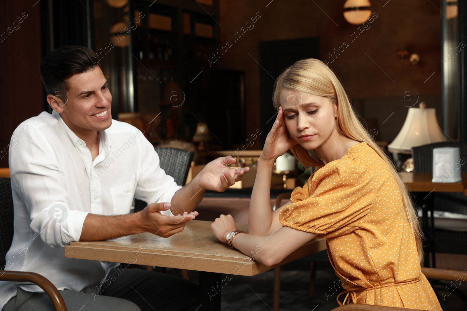 Photo of Young woman having boring date with talkative man in cafe