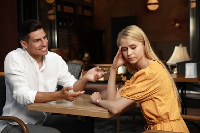 Photo of Young woman having boring date with talkative man in cafe