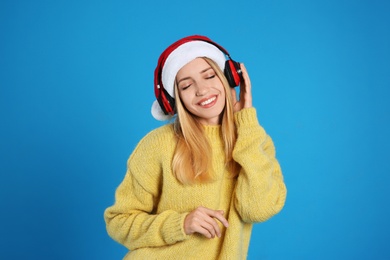 Photo of Happy woman with headphones on blue background. Christmas music
