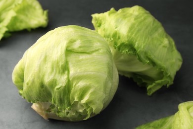 Photo of Fresh green iceberg lettuce heads and leaves on grey table, closeup