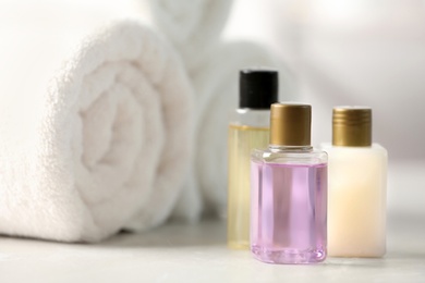 Photo of Mini bottles with cosmetic products and towels on table. Hotel amenities