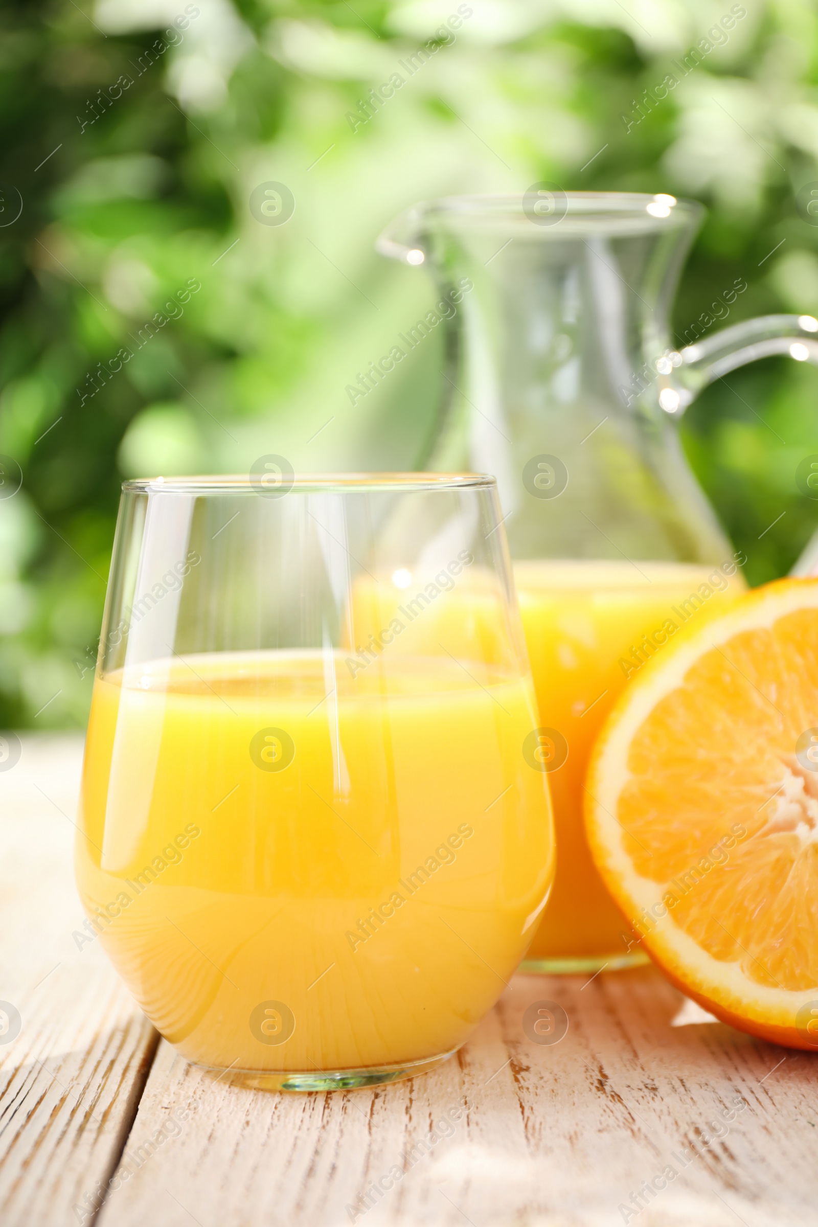 Photo of Glassware of fresh orange juice on white wooden table