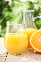 Photo of Glassware of fresh orange juice on white wooden table