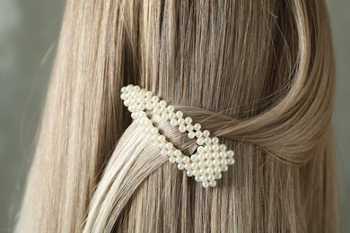 Young woman with beautiful hair clip on grey background, closeup