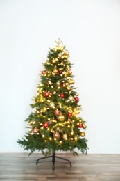 Blurred view of beautiful Christmas tree with fairy lights, indoors