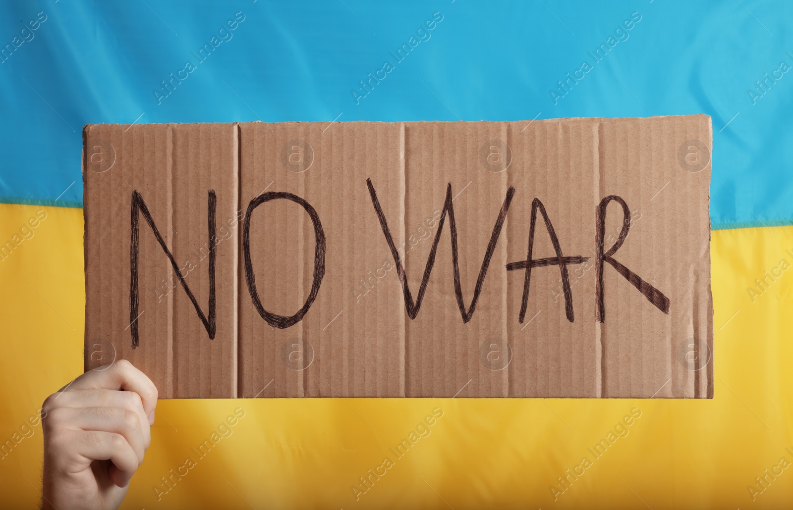 Photo of Teenage boy holding poster No War against Ukrainian flag, closeup