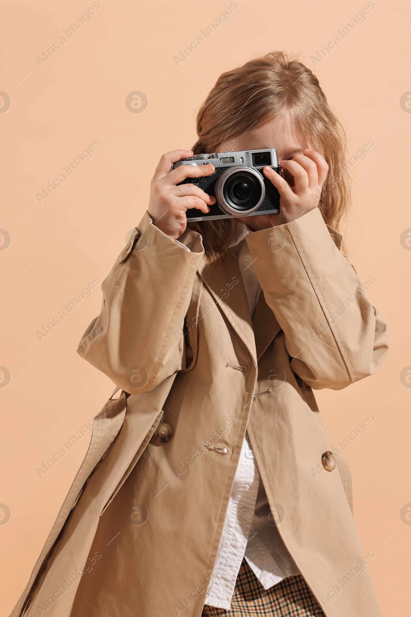 Photo of Fashion concept. Stylish girl with vintage camera on pale orange background