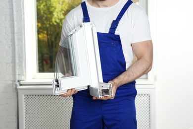 Photo of Installation worker with sample of modern window profile indoors