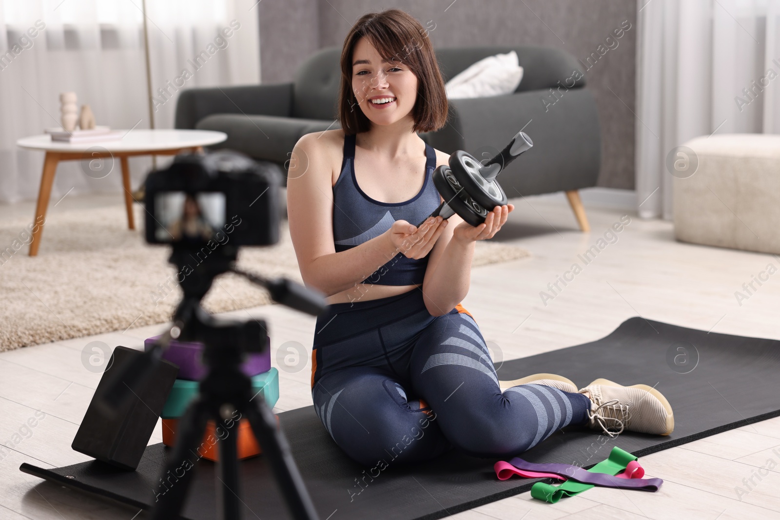 Photo of Happy sports blogger with ab roller recording fitness lesson at home