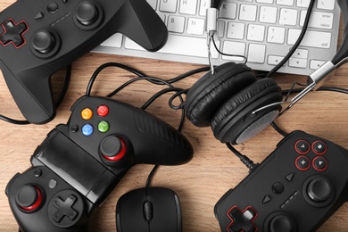 Photo of Gamepads, mouse and headphones on wooden table