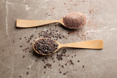 Black salt in wooden spoons on grey table, flat lay