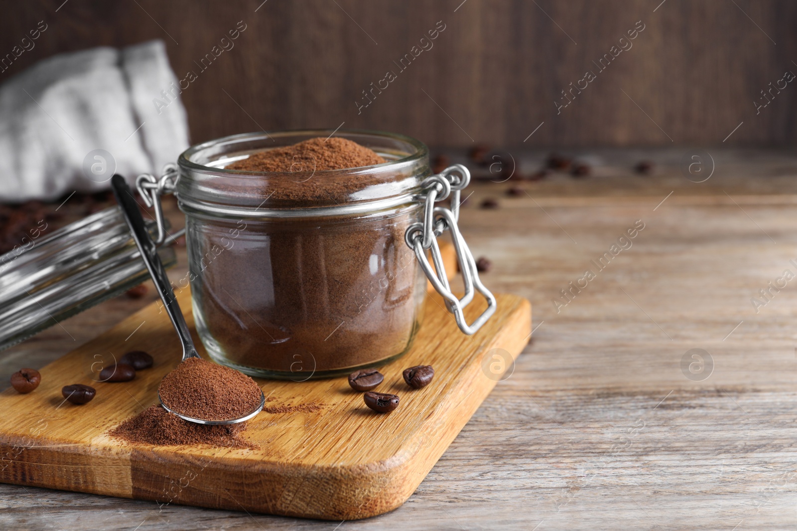 Photo of Glass jar of instant coffee and spoon on wooden table. Space for text