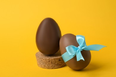 Two tasty chocolate eggs on orange background