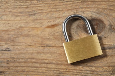 Photo of Steel padlock on wooden table, top view. Space for text