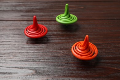 Photo of Three bright spinning tops on wooden table
